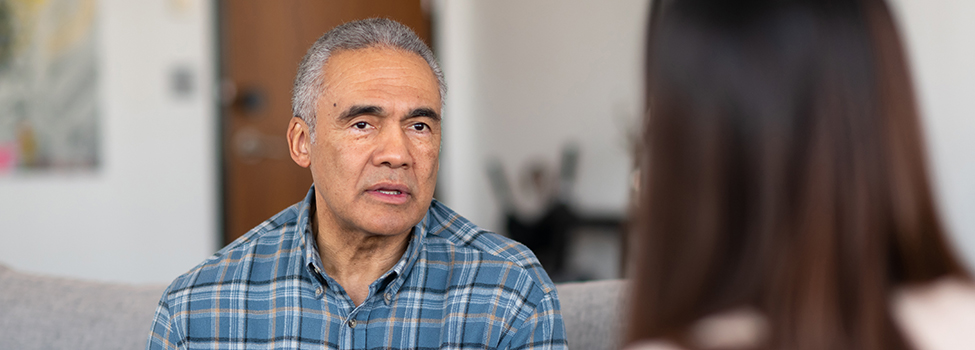 An elderly man of African descent talks to a therapist