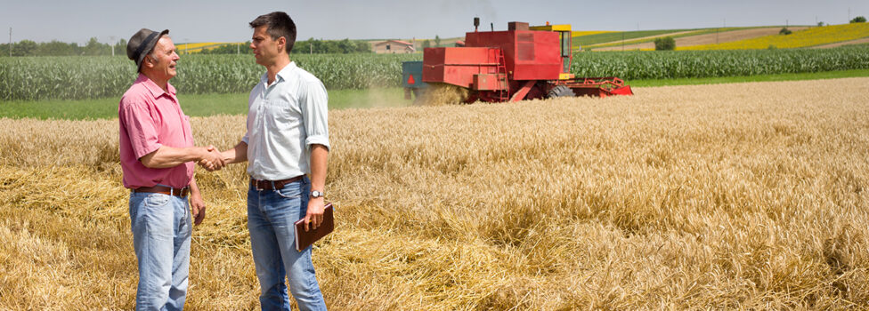 Farmer and businessman shaking hands on wheat field