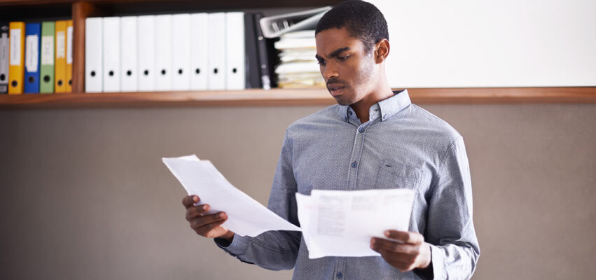 Shot of a handsome young businessman looking over some documents in his office
