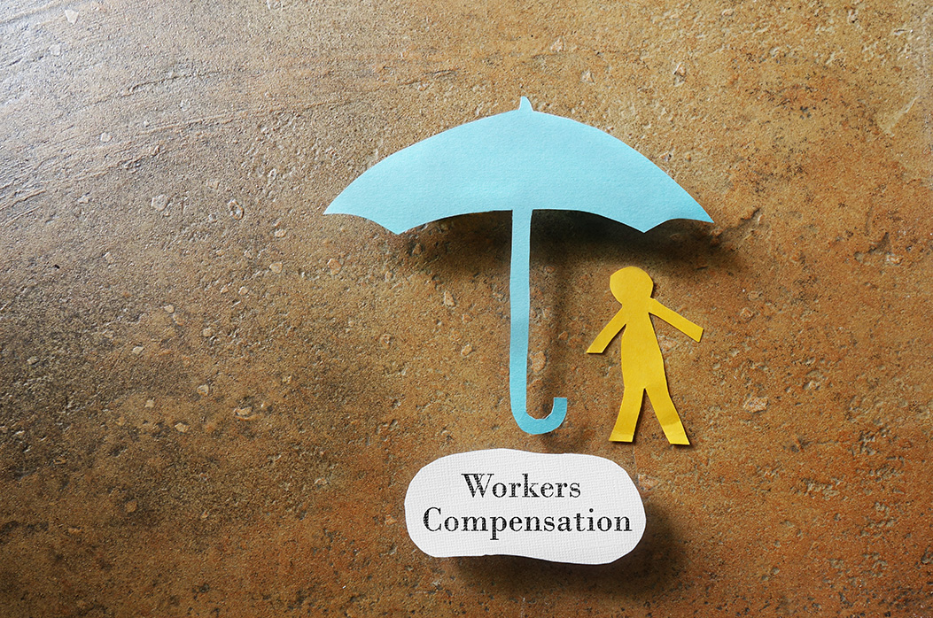 Paper man under an umbrella with Workers Compensation note underneath