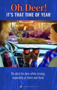 Poster: Oh Deer! It's That Time of Year. Shows couple holding to-go coffee cups while in car and through windshield see a deer in the middle of the road