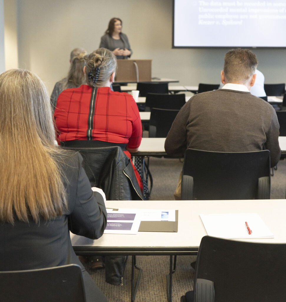 Training event attendees attentively listen to speaker at front of room